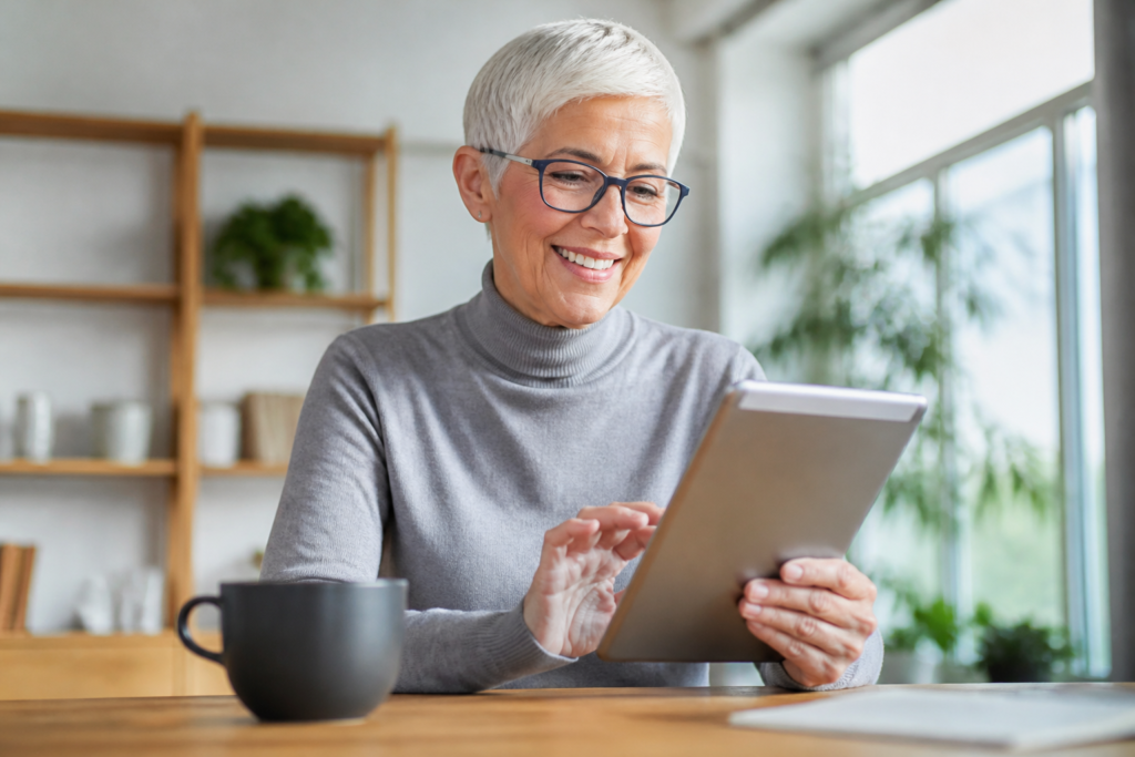 A cheerful elderly woman, reviewing her email newsletter campaign on a tablet